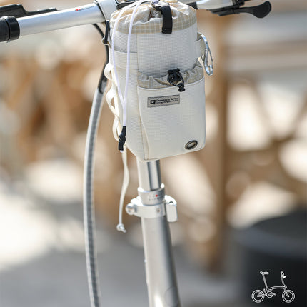 Pearl White Cosmopolis bike bottle bag mounted on a handlebar